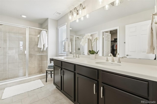 full bathroom with a sink, a spacious closet, a shower stall, and double vanity