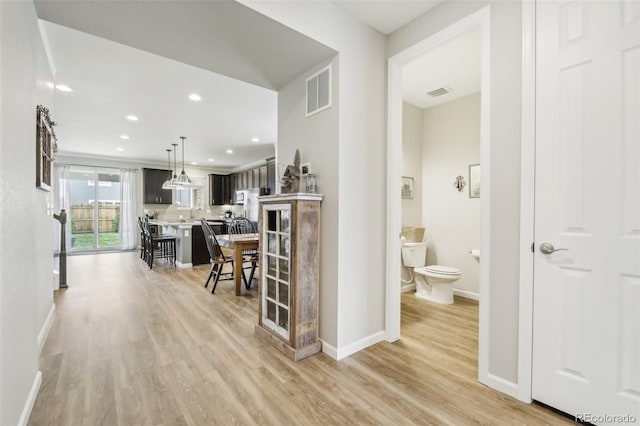 corridor featuring light wood-style floors, recessed lighting, visible vents, and baseboards