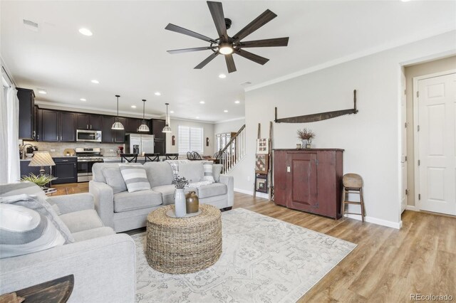 living room with baseboards, stairway, ornamental molding, light wood-type flooring, and recessed lighting