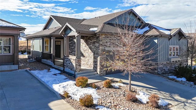 view of front facade with driveway, a garage, a shingled roof, stone siding, and board and batten siding