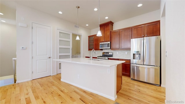 kitchen featuring appliances with stainless steel finishes, decorative light fixtures, and light hardwood / wood-style floors