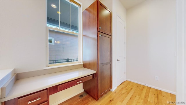 interior space featuring built in desk and light hardwood / wood-style flooring