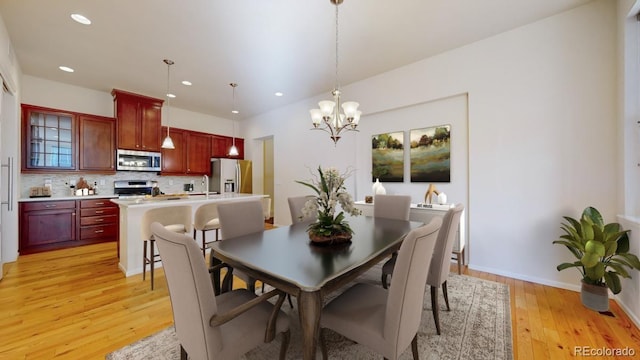 dining space with a chandelier, light wood-type flooring, and sink