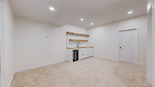 bar featuring sink, wine cooler, wooden counters, light colored carpet, and decorative backsplash