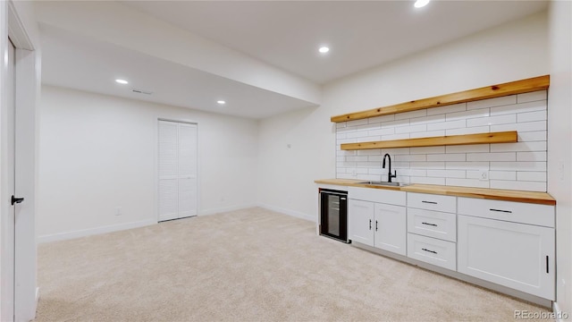 bar featuring wine cooler, white cabinetry, sink, and wood counters