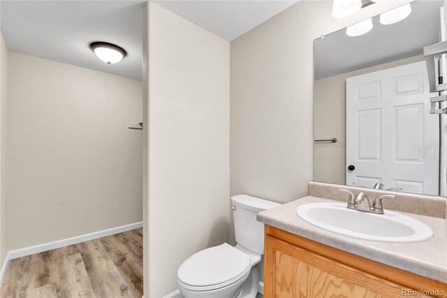 22974 E Dorado Dr, Aurora, CO 80015 - bathroom with toilet, vanity, wood finished floors, and baseboards