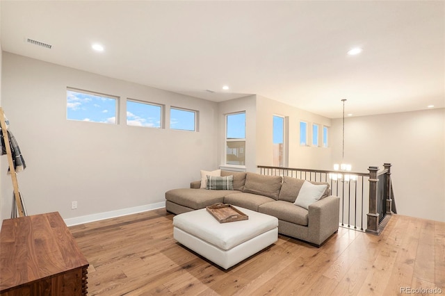 living room featuring light wood-type flooring, a chandelier, and plenty of natural light