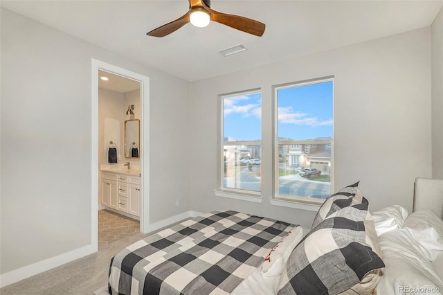 bedroom featuring ensuite bath, sink, light colored carpet, and ceiling fan