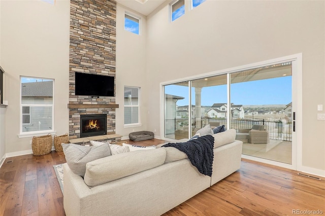 living room with hardwood / wood-style flooring, a high ceiling, and a fireplace