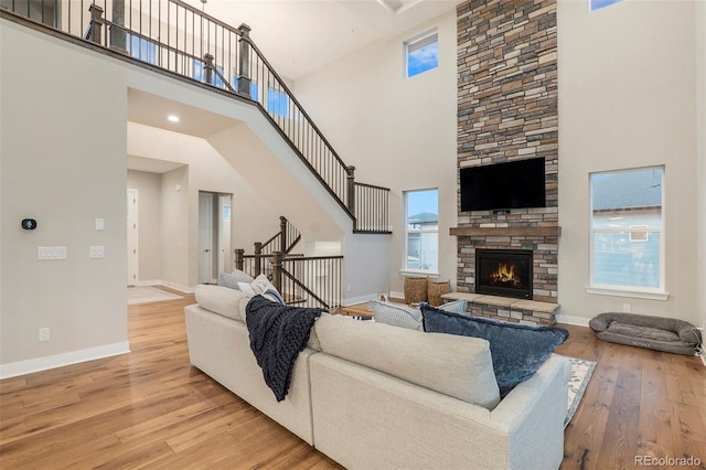 living room featuring light hardwood / wood-style floors, a fireplace, and a high ceiling