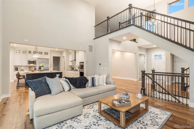 living room with sink, light hardwood / wood-style floors, and a towering ceiling