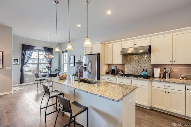 15855 Wild Horse Dr, Broomfield, CO 80023 - kitchen with stainless steel appliances, dark wood-style floors, a sink, decorative backsplash, and under cabinet range hood