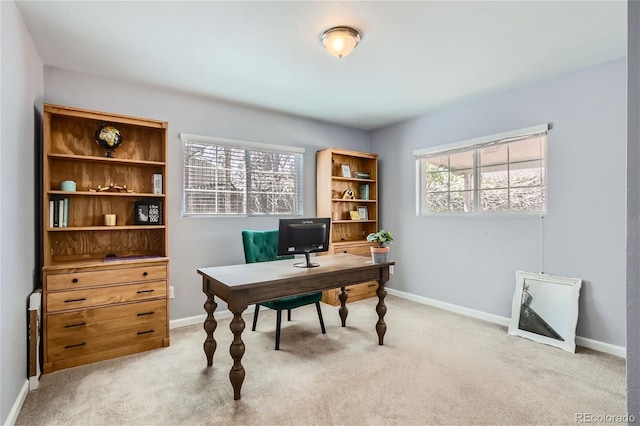 office space featuring plenty of natural light, baseboards, and light colored carpet