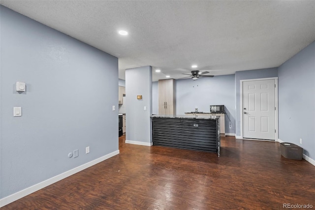 living room featuring a textured ceiling, dark hardwood / wood-style floors, and ceiling fan