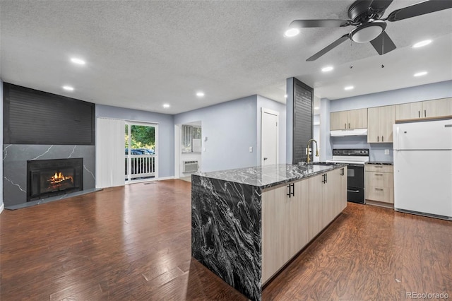 kitchen featuring a kitchen island with sink, white appliances, dark hardwood / wood-style flooring, a large fireplace, and ceiling fan