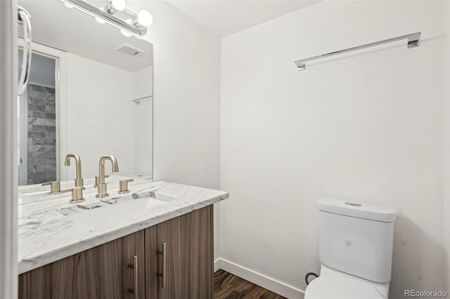 bathroom with wood-type flooring, vanity, and toilet