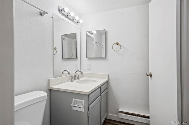 bathroom featuring baseboard heating, hardwood / wood-style flooring, vanity, and toilet