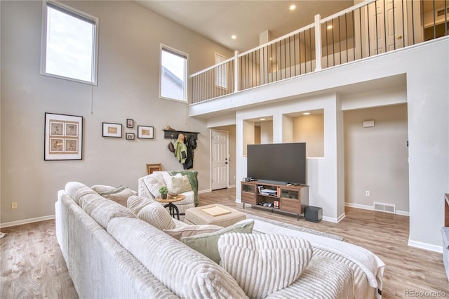 living room featuring a towering ceiling and light hardwood / wood-style flooring