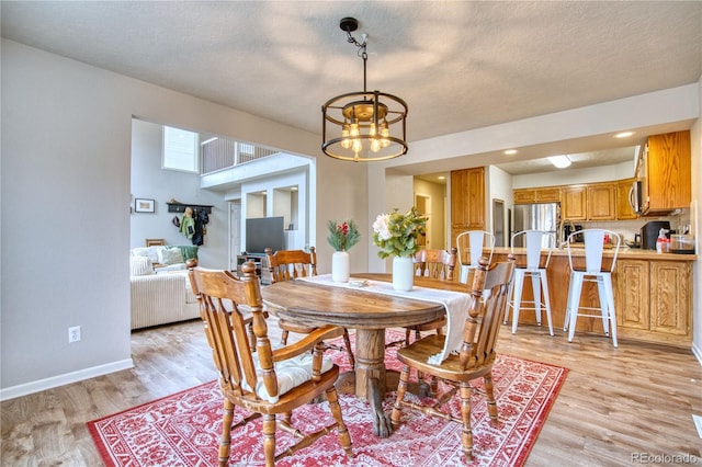 dining space featuring a textured ceiling, light wood-type flooring, and a chandelier