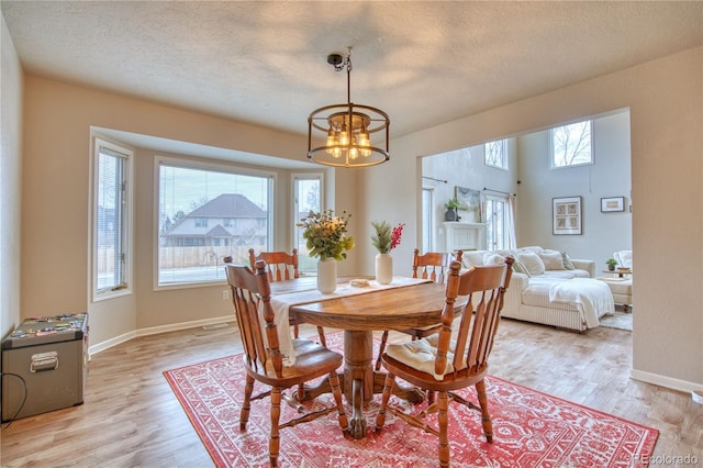 dining space with a notable chandelier, light hardwood / wood-style floors, and a textured ceiling