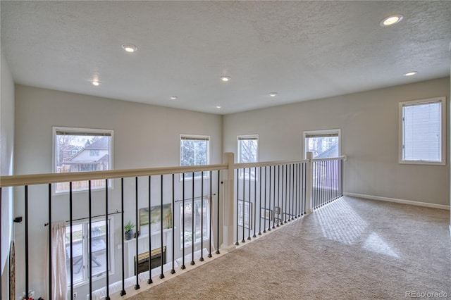 hall featuring a textured ceiling and carpet floors