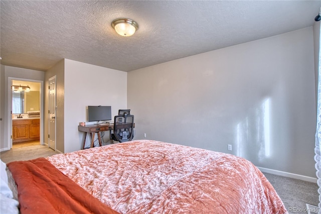 bedroom featuring connected bathroom, carpet flooring, a textured ceiling, and sink