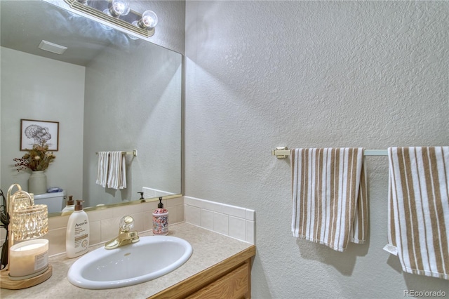 bathroom featuring decorative backsplash, vanity, and toilet