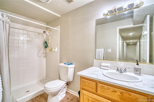 bathroom featuring hardwood / wood-style floors, vanity, a textured ceiling, walk in shower, and toilet