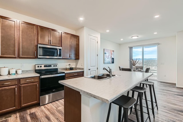 kitchen featuring a center island with sink, hardwood / wood-style flooring, sink, and appliances with stainless steel finishes