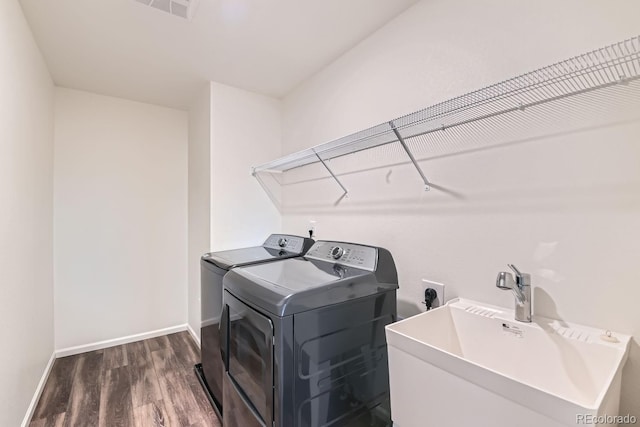 laundry room featuring dark hardwood / wood-style floors, washer and dryer, and sink