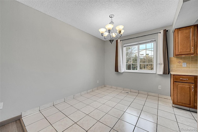 unfurnished dining area featuring light tile patterned floors, a chandelier, and a textured ceiling