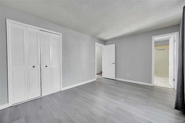 unfurnished bedroom with a textured ceiling, a closet, and light wood-type flooring