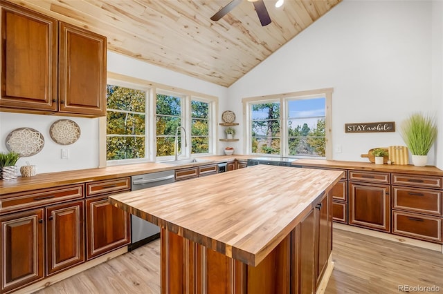 kitchen featuring sink, light hardwood / wood-style flooring, dishwasher, butcher block counters, and a center island