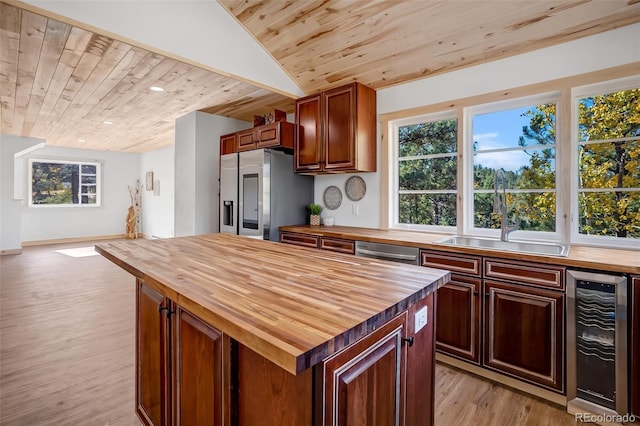 kitchen with appliances with stainless steel finishes, a kitchen island, wood counters, wooden ceiling, and beverage cooler