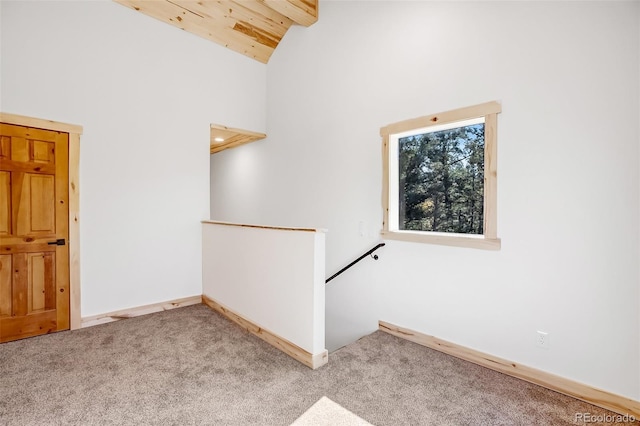 carpeted spare room featuring beamed ceiling, high vaulted ceiling, and wood ceiling