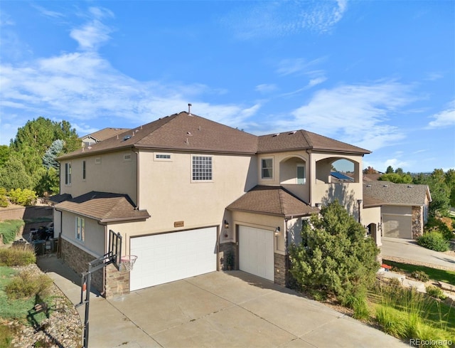 10215 W Wesley Dr, Lakewood, CO 80227 - view of front facade featuring stone siding, a garage, concrete driveway, and stucco siding