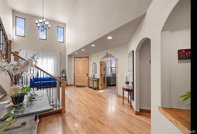 foyer entrance with an inviting chandelier, a towering ceiling, and hardwood / wood-style floors