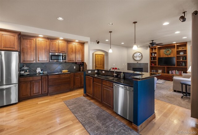 kitchen featuring appliances with stainless steel finishes, light wood-type flooring, ceiling fan, a center island with sink, and sink