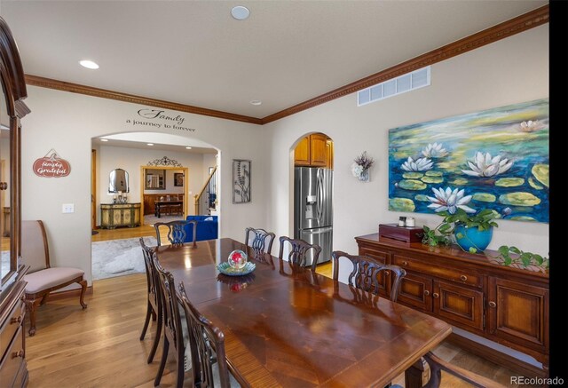 10215 W Wesley Dr, Lakewood, CO 80227 - dining space featuring crown molding, stairs, arched walkways, light wood finished floors, and visible vents