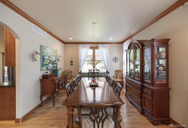 dining area featuring light wood-type flooring and ornamental molding