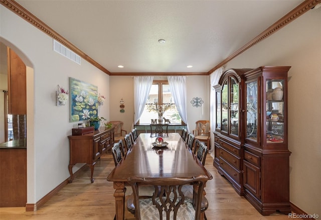 10215 W Wesley Dr, Lakewood, CO 80227 - dining room with visible vents, crown molding, arched walkways, and light wood-style floors