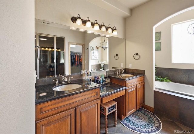 bathroom featuring a relaxing tiled tub, tile patterned flooring, and vanity