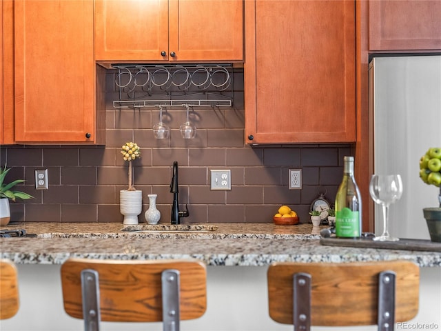 kitchen with tasteful backsplash, sink, and light stone counters