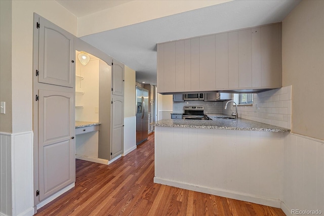 1923 S Newark Way, Aurora, CO 80014 - kitchen featuring stainless steel appliances, wood finished floors, a peninsula, decorative backsplash, and wainscoting
