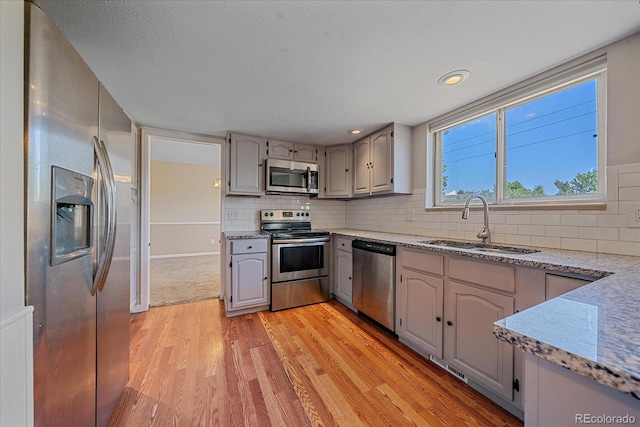 1923 S Newark Way, Aurora, CO 80014 - kitchen featuring appliances with stainless steel finishes, light wood-style floors, gray cabinetry, backsplash, and light stone counters