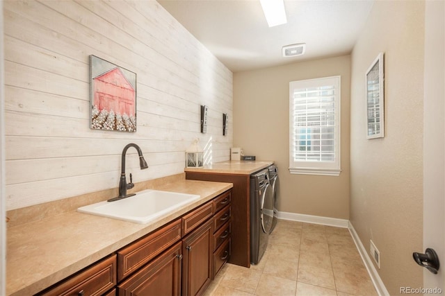 clothes washing area with light tile patterned floors, washing machine and dryer, a sink, baseboards, and cabinet space