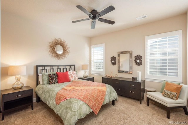 bedroom featuring a ceiling fan, visible vents, and light carpet