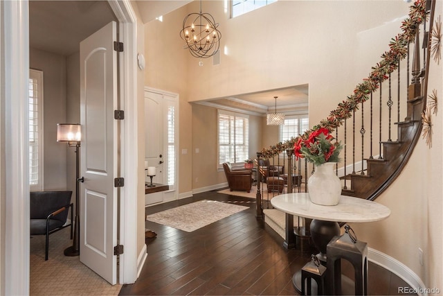 foyer featuring stairway, an inviting chandelier, ornamental molding, wood finished floors, and baseboards