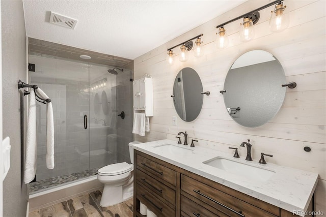 bathroom with toilet, a sink, visible vents, and a shower stall