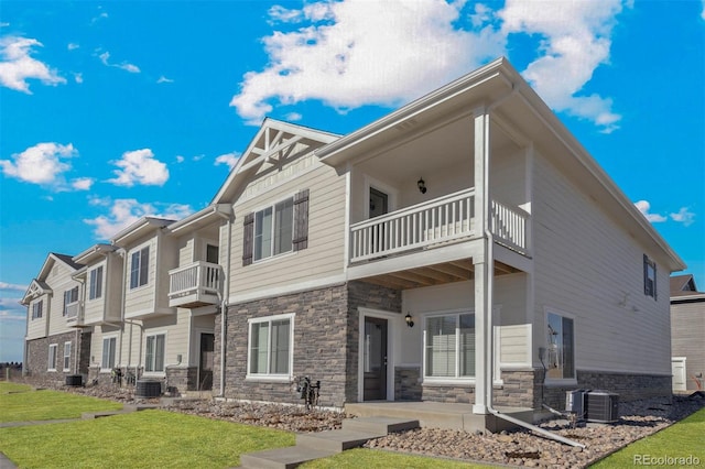 rear view of house featuring a balcony, central AC unit, and a lawn